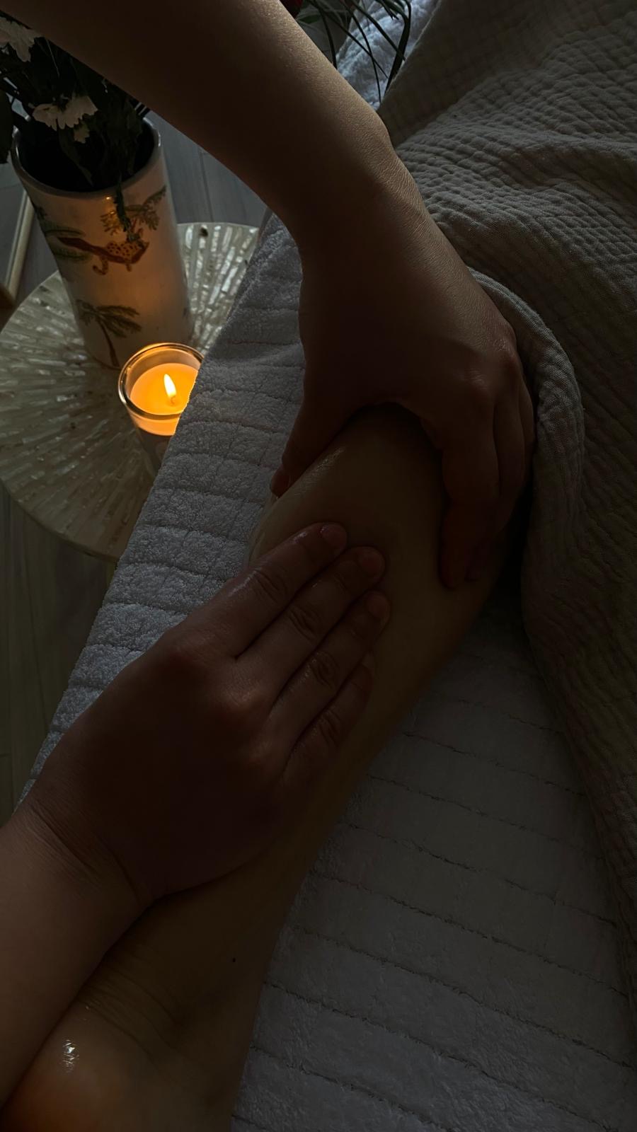Les mains de Zoé réalisant un massage à l’huile dans une ambiance chaleureuse